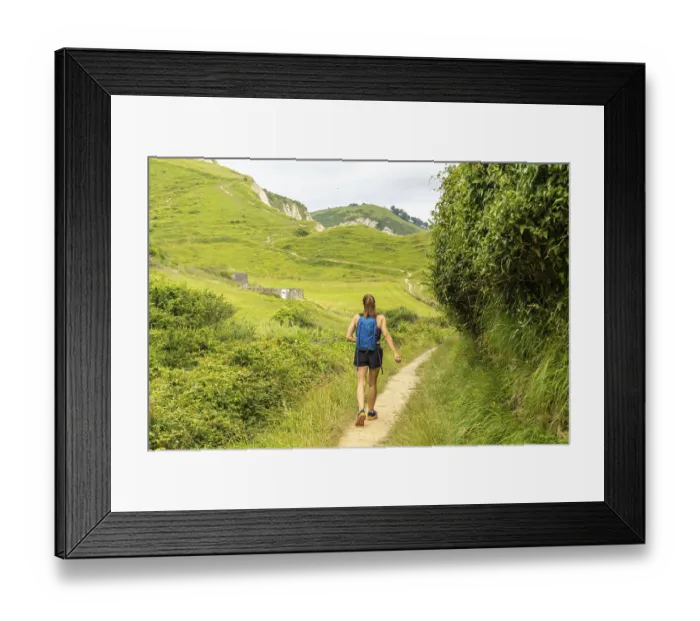 Framed Print : Female tourist walking on a path surrounded by lush vegetation