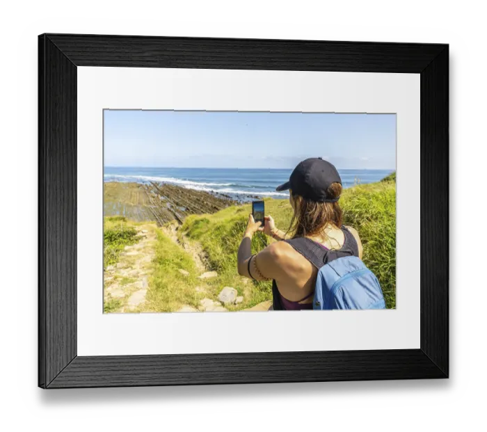 Framed Print : Hiker taking pictures of the impressive flysch cliffs at sakoneta beach in zumaia