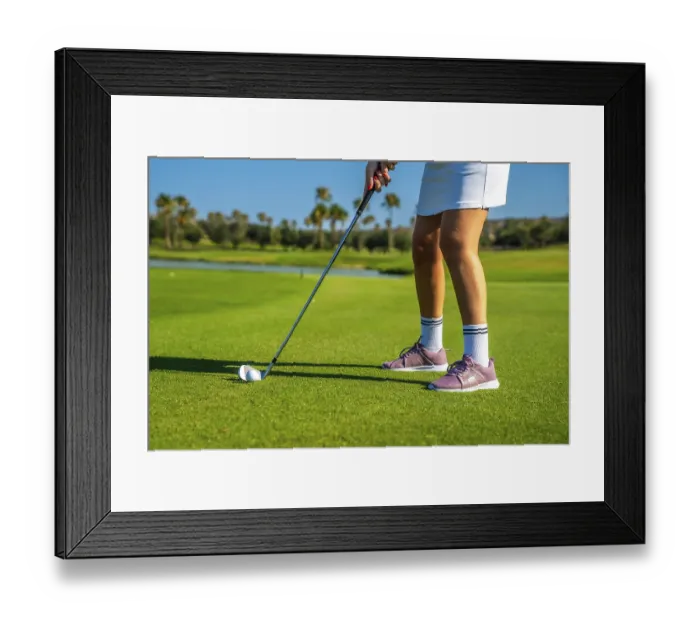Framed Print : Female golfer concentrating intensely while hitting the golf ball on a bright Framed Print : Female golfer concentrating intensely while hitting the golf ball on a bright