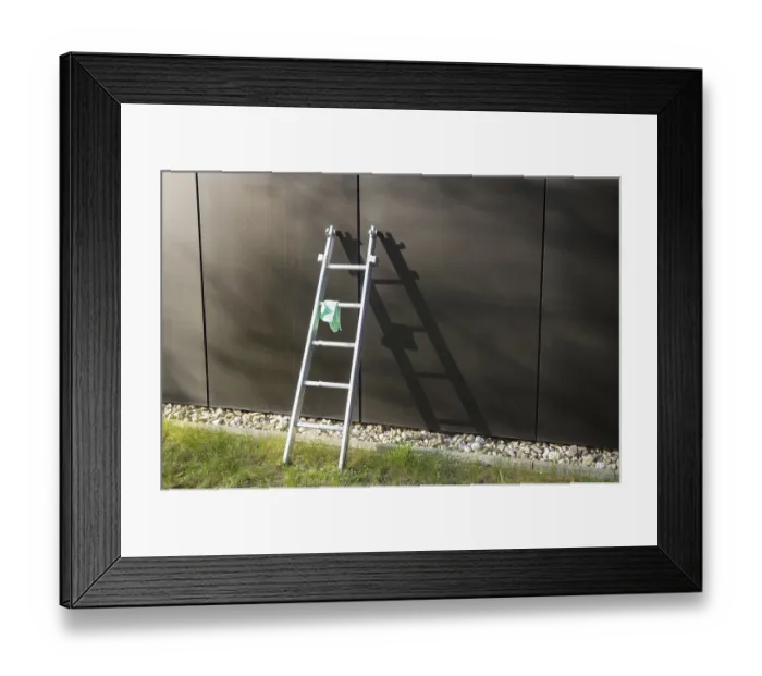 Framed Print : Metal ladder is leaning against a modern building with a cleaning cloth hanging on it