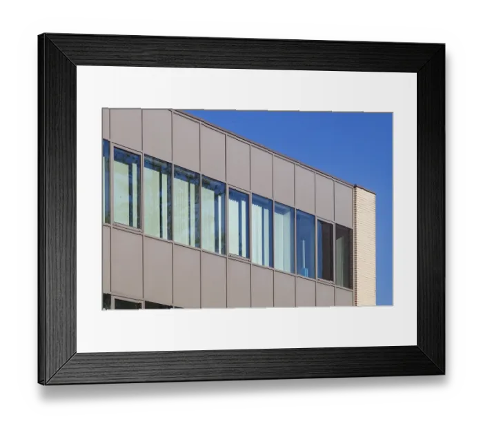 Framed Print : Modern office building exterior showcasing a contemporary design with large windows reflecting the vibrant blue sky