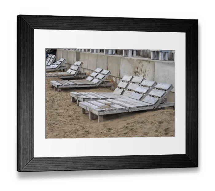 Framed Print : Empty wooden beach chairs sit on a sandy shore