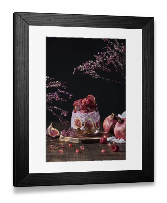 Framed Print : Side view of fresh fruit jam in small jar with full and cut figs on plate at black kitchen table next to pomegranates