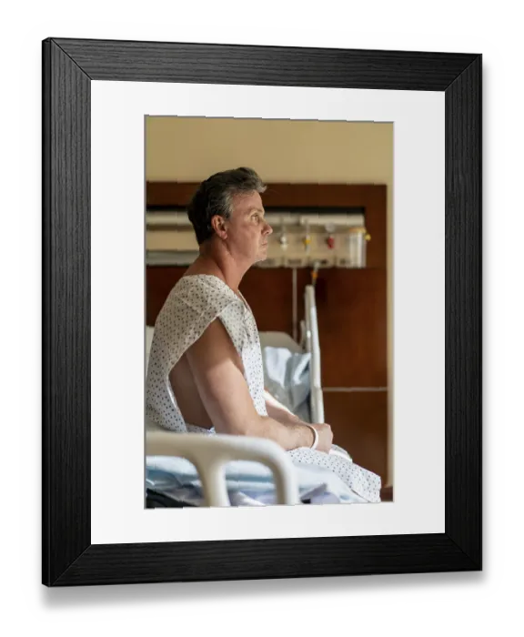 Framed Print : Pensive patient sitting in hospital bed looking away