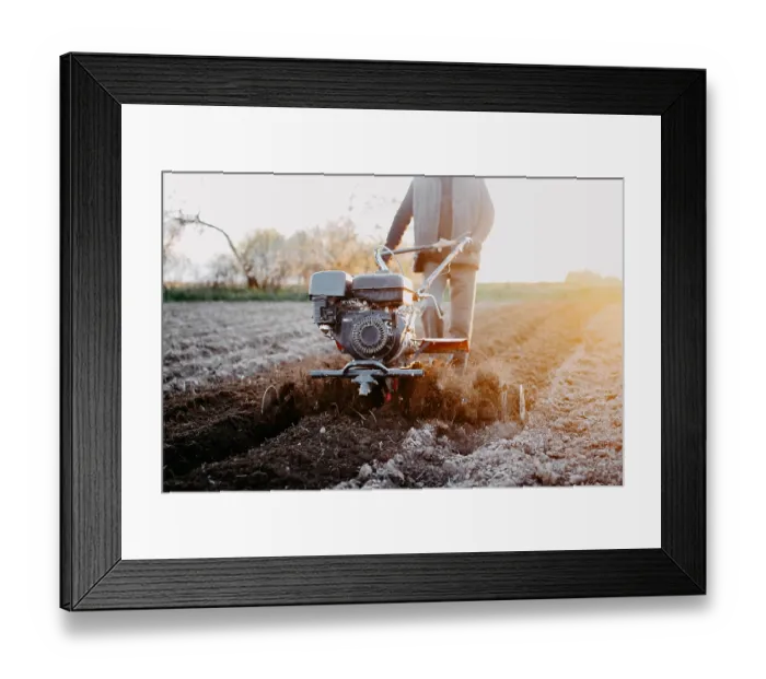 Framed Print : Person using a tiller on a farm field at sunrise