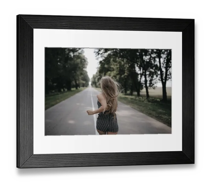 Framed Print : A girl in a striped dress runs energetically on a road lined with trees