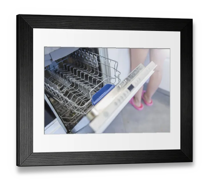 Framed Print : A person standing near an open dishwasher with pink slippers visible