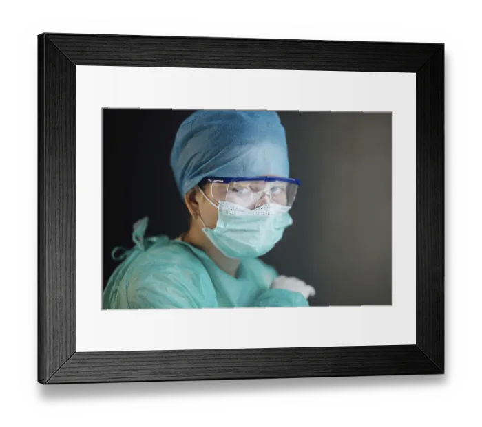 Framed Print : A healthcare worker wearing a mask and goggles looking intently at the camera