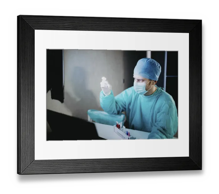 Framed Print : Scientist in blue scrubs examining test tube in a laboratory setting