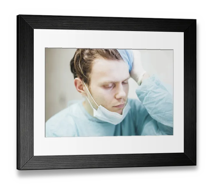 Framed Print : A doctor in scrubs showing concern with hand on head