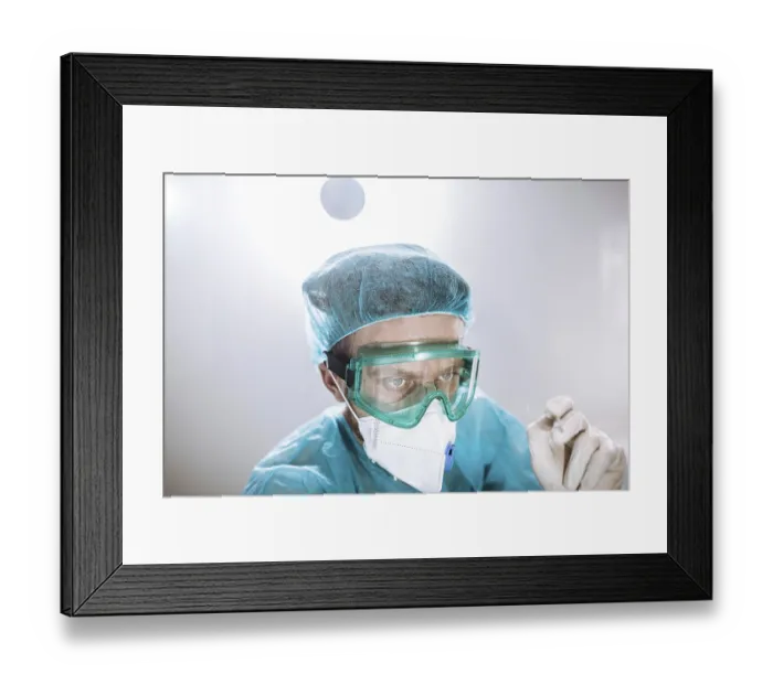 Framed Print : A healthcare worker in protective gear focused on a task