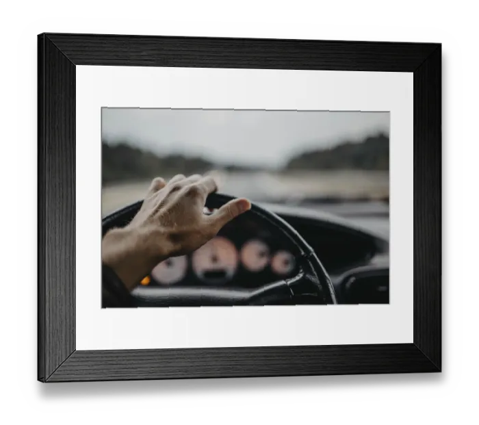 Framed Print : A hand gripping the steering wheel with a blurred view of the road ahead