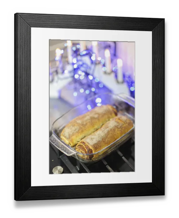 Framed Print : Two cinnamon rolls in a glass dish surrounded by candles and blue lights