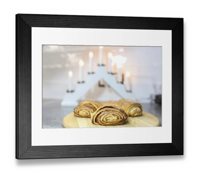 Framed Print : Cinnamon rolls on a wooden board with gentle light from decorative candles
