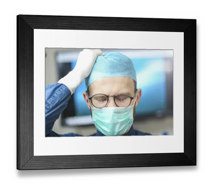 Framed Print : A surgeon adjusting his cap, appearing concentrated and careful Framed Print : A surgeon adjusting his cap, appearing concentrated and careful
