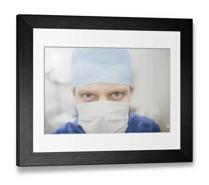 Framed Print : Intense gaze of a doctor wearing a mask and blue surgical cap