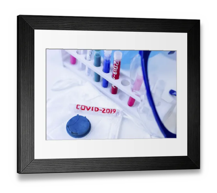 Framed Print : A rack with colored vials and a COVID-2019 test tube under safety glasses against a blue background