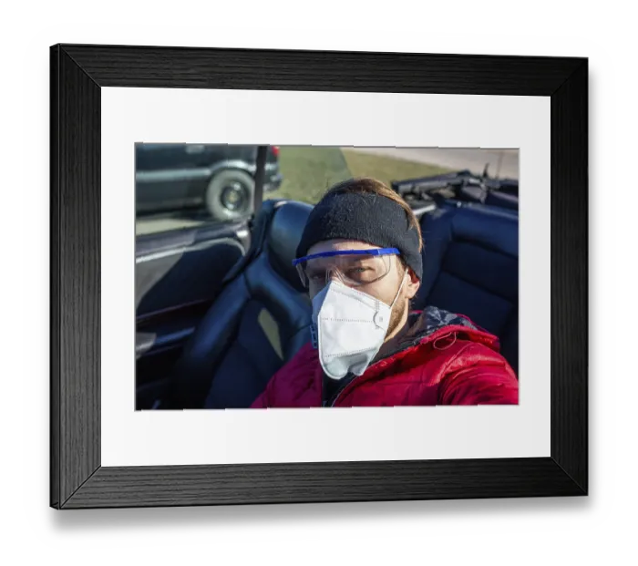 Framed Print : Casually dressed man wearing a face mask and goggles in a car on a sunny day