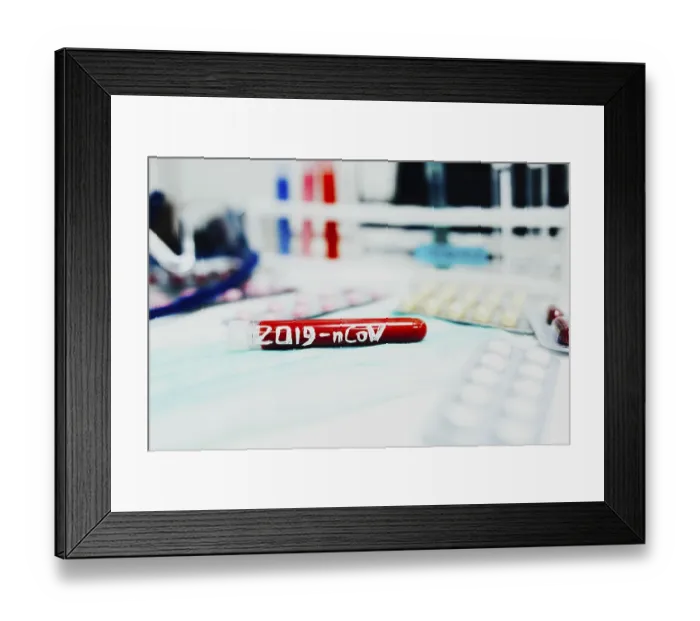 Framed Print : Close-up of a labeled test tube 2019-nCoV on a blue cloth with lab equipment nearby