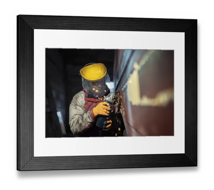 Framed Print : A worker uses an angle grinder with sparks flying in an industrial setting