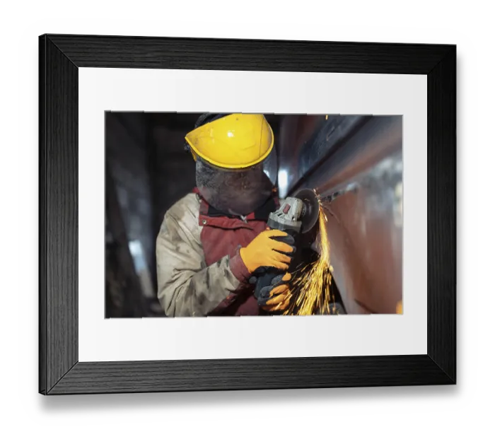 Framed Print : A worker with protective gear operates an angle grinder on a metal surface Framed Print : A worker with protective gear operates an angle grinder on a metal surface