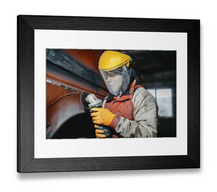 Framed Print : A worker in protective gear using a grinder on a vehicle