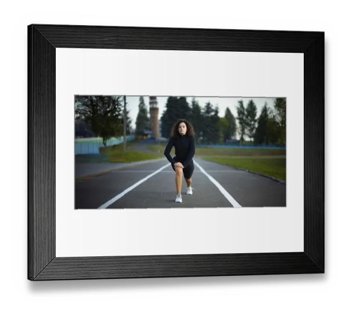 Framed Print : Woman performing a lunge exercise on a road with trees in the background