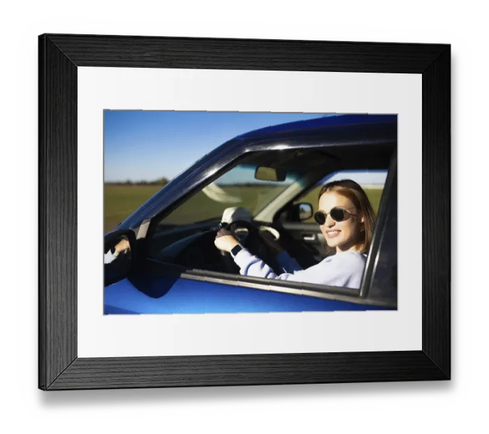 Framed Print : Woman smiling in a blue car while driving on a rural road