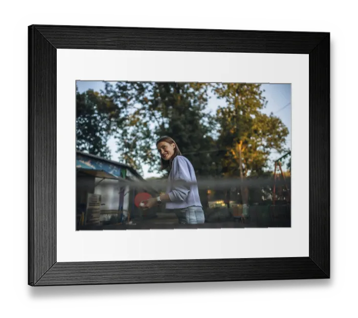 Framed Print : Woman smiling while engaging in table tennis in a park setting
