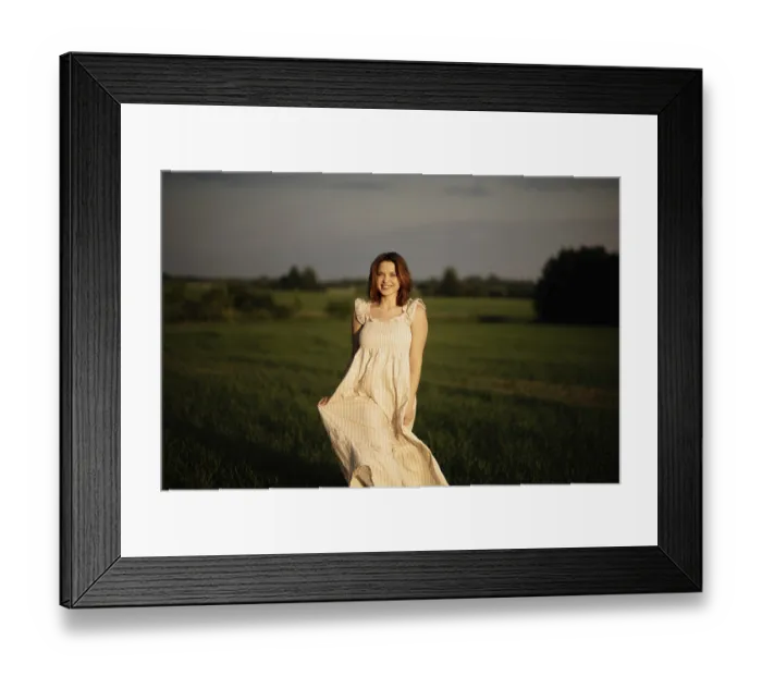 Framed Print : A smiling woman in a flowing dress stands in a field during sunset