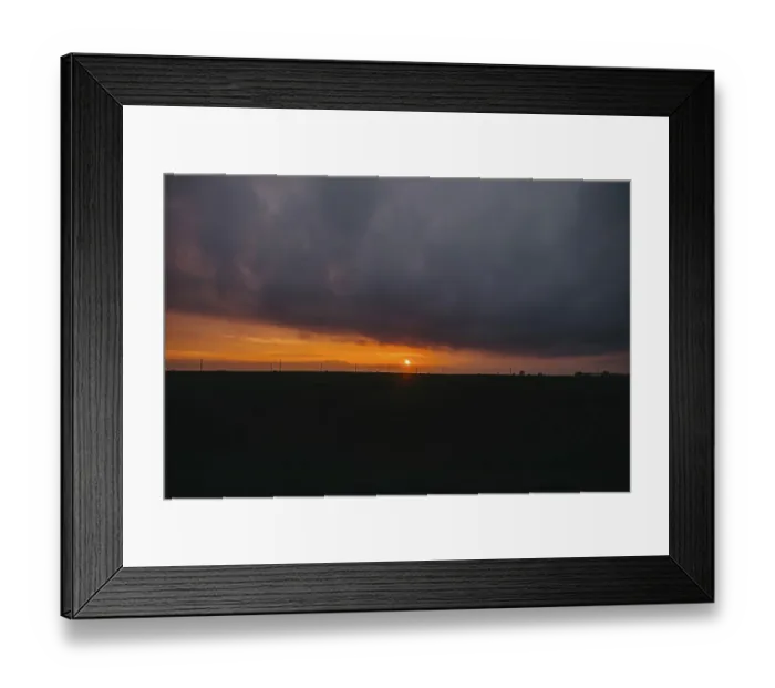 Framed Print : The sun sets behind clouds creating a dramatic