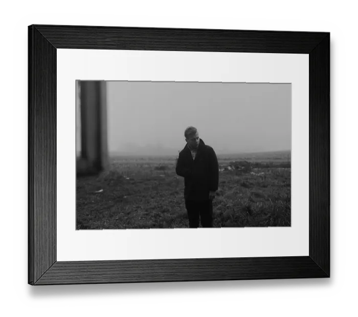Framed Print : Man in an overcoat standing in a foggy field creates a somber mood Framed Print : Man in an overcoat standing in a foggy field creates a somber mood