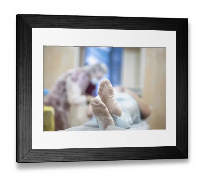 Framed Print : Patient lying in a hospital setting with medical staff in a blurred background