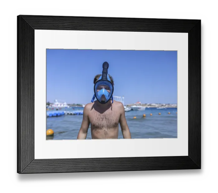 Framed Print : Person on a beach wearing a blue snorkel mask