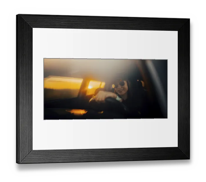 Framed Print : Silhouetted woman in a car at sunset