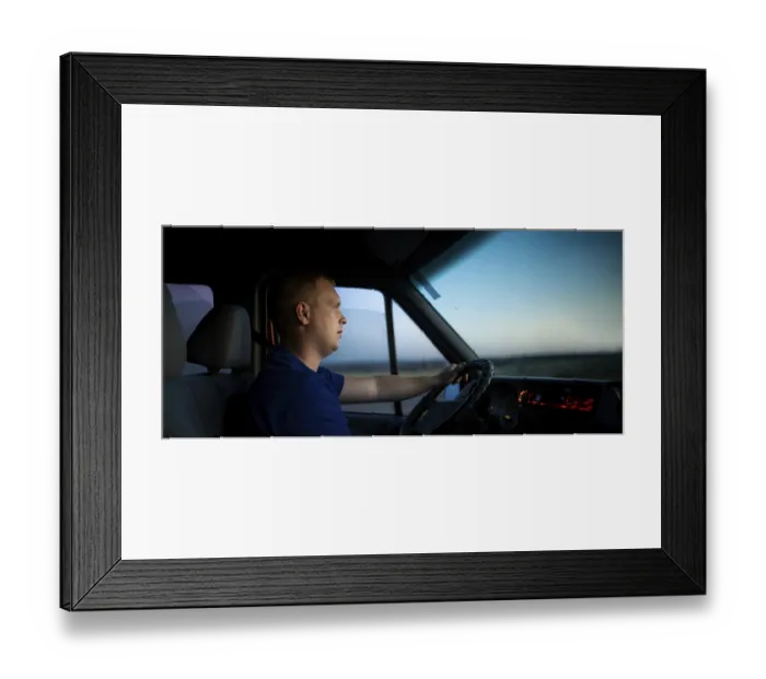 Framed Print : A man focused on driving, illuminated by a sunset