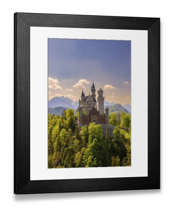 Framed Print : Neuschwanstein Castle amidst green trees in front of a clear sky and mountain scenery