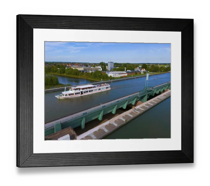 Framed Print : A passenger ship sails on a canal over a large bridge