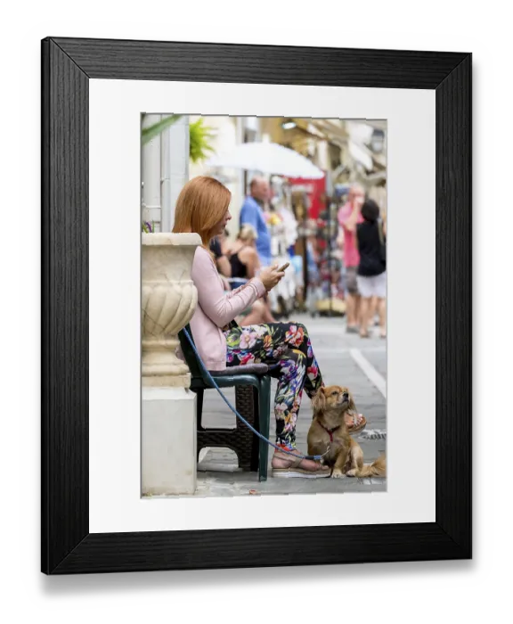 Framed Print : Street scene with woman and dog and mobile phone in the old town of Rethymno