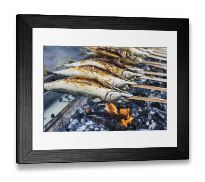 Framed Print : Stockfisch, fish dish prepared on wooden stick being barbecued