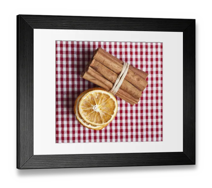 Framed Print : Slices of dried orange and cinnamon sticks on a chequered cloth