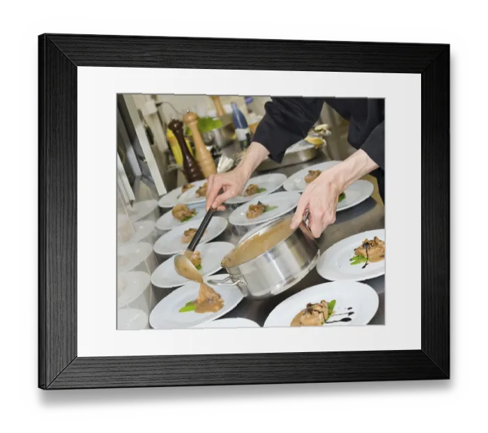Framed Print : Chef pours sauce over meat pieces on plates Framed Print : Chef pours sauce over meat pieces on plates