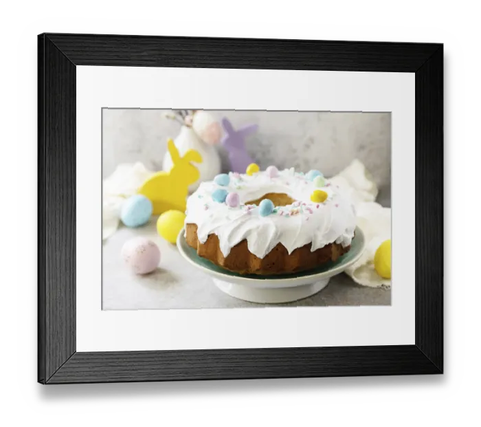 Framed Print : Glazed easter lemon cake decorated with confectionery and mini chocolate eggs candy on gray stone background