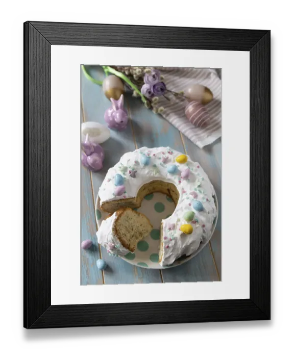 Framed Print : Glazed easter lemon cake decorated with confectionery and mini chocolate eggs candy on a wooden table