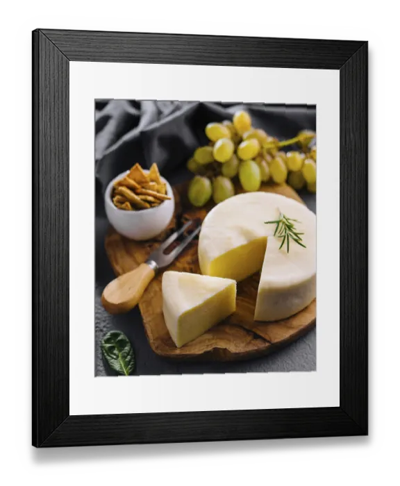 Framed Print : Round cheese on a wooden board and green grapes
