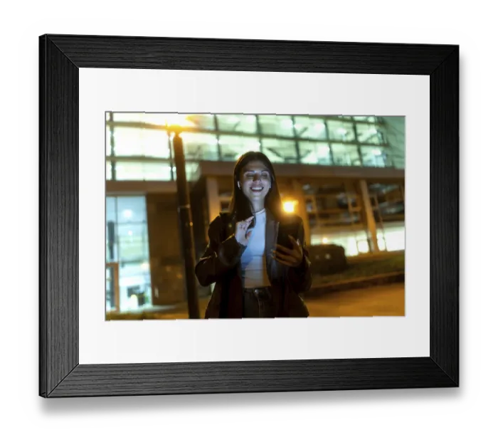 Framed Print : Young woman smiling broadly, wearing wireless earbuds and dark jacket