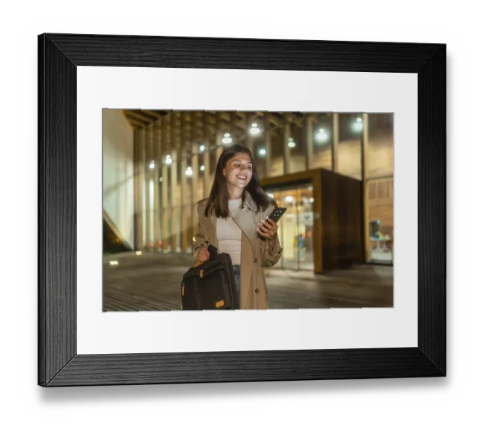 Framed Print : Young businesswoman smiling while checking her smartphone Framed Print : Young businesswoman smiling while checking her smartphone