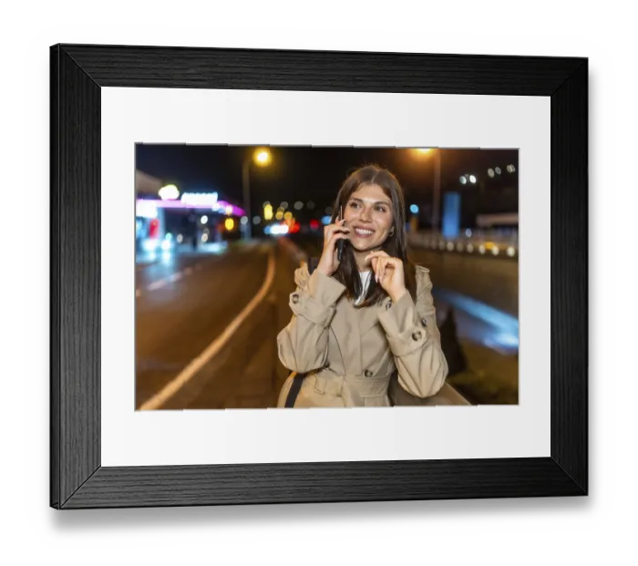 Framed Print : Young woman in a trench coat smiling happily while having a phone call