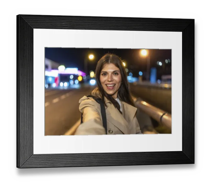 Framed Print : Young woman smiling and taking a selfie on a lively city night