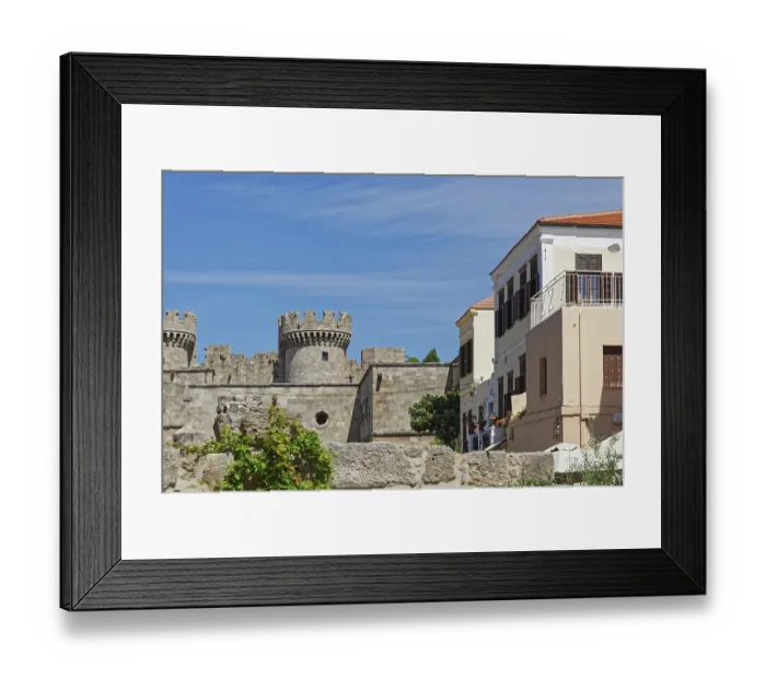 Framed Print : Castle with medieval stone towers next to a Mediterranean building under a blue sky Framed Print : Castle with medieval stone towers next to a Mediterranean building under a blue sky